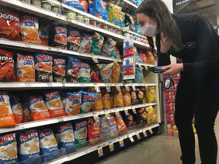 Mikela Earley searches for a bag of Ruffles original potato chips to fill an order made by a person quarantined at one of the NCAA tournament's four bubble hotels.